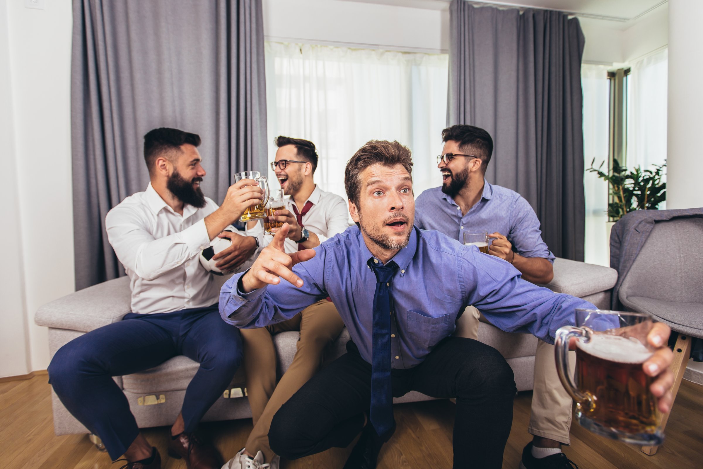 Group of football fans watching soccer game on television and celebrating goal.