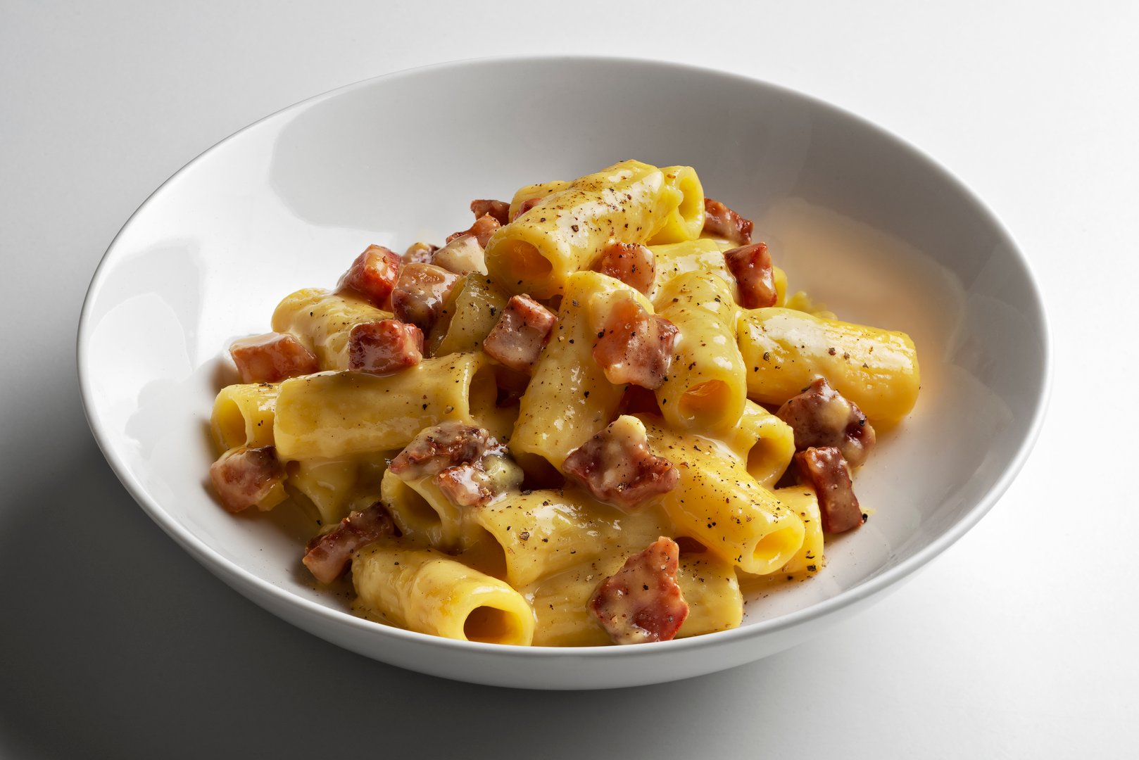 Rigatoni Carbonara Pasta in a White Bowl isolated on white background