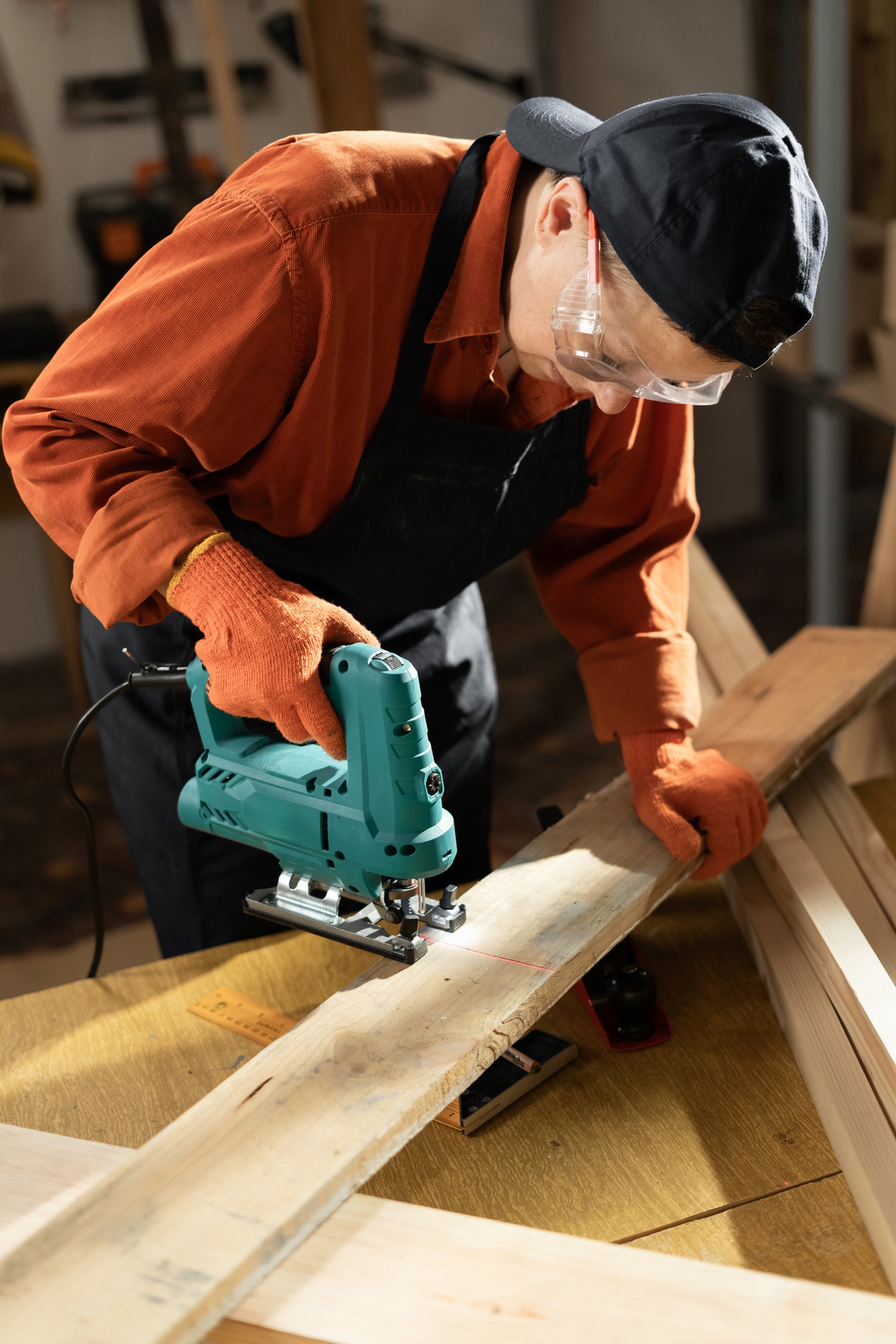 Female carpenter using a jigsaw to cut wood in her workshop, demonstrating precision and craftsmanship in woodworking projects.