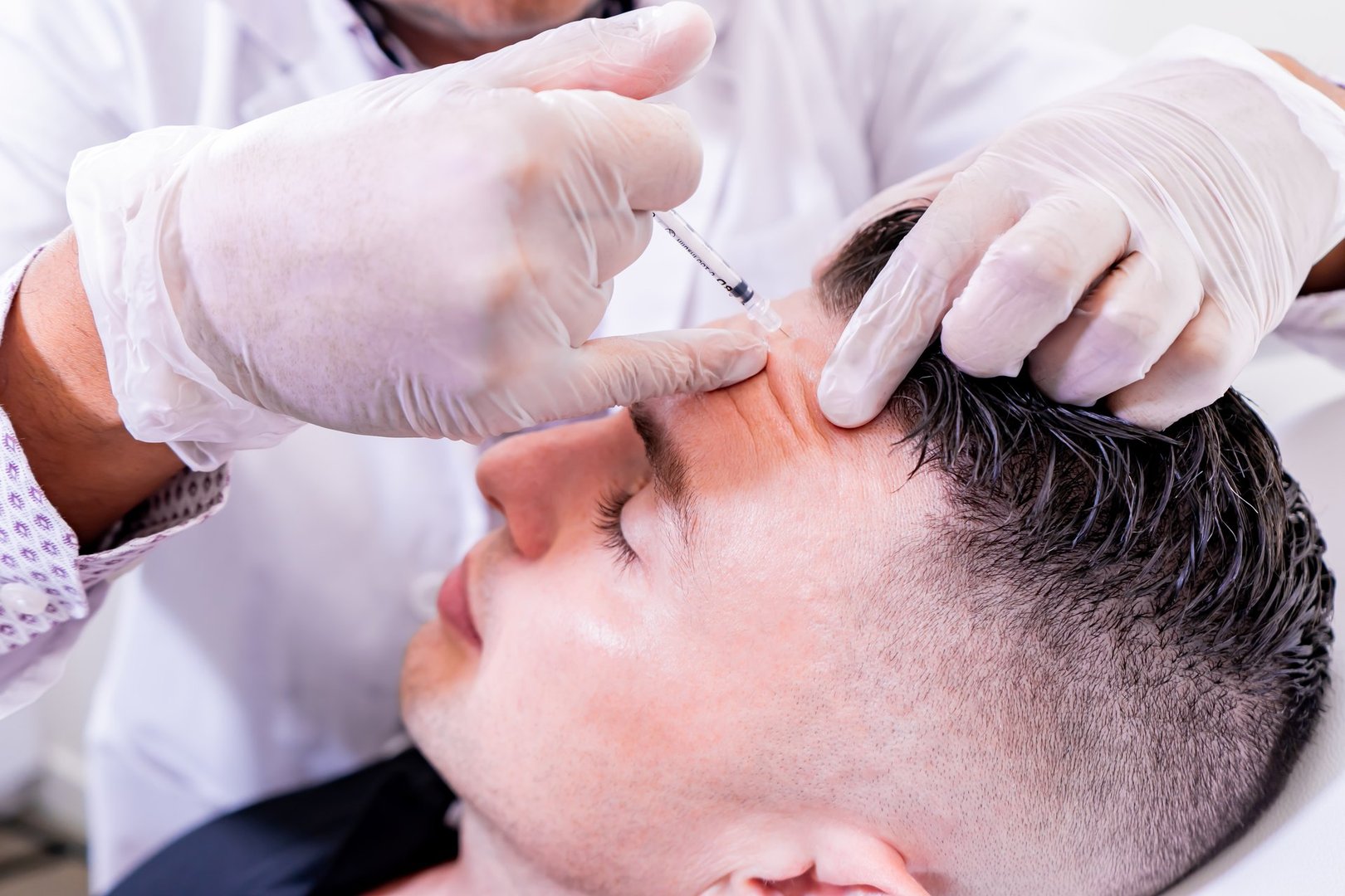 Caucasian man undergoing beauty spa botulinum neurotoxin Botox treatment for anti-aging, to smooth wrinkles as a cometic solution. Injecting forehead to relax muscles with a non-invasive procedure.