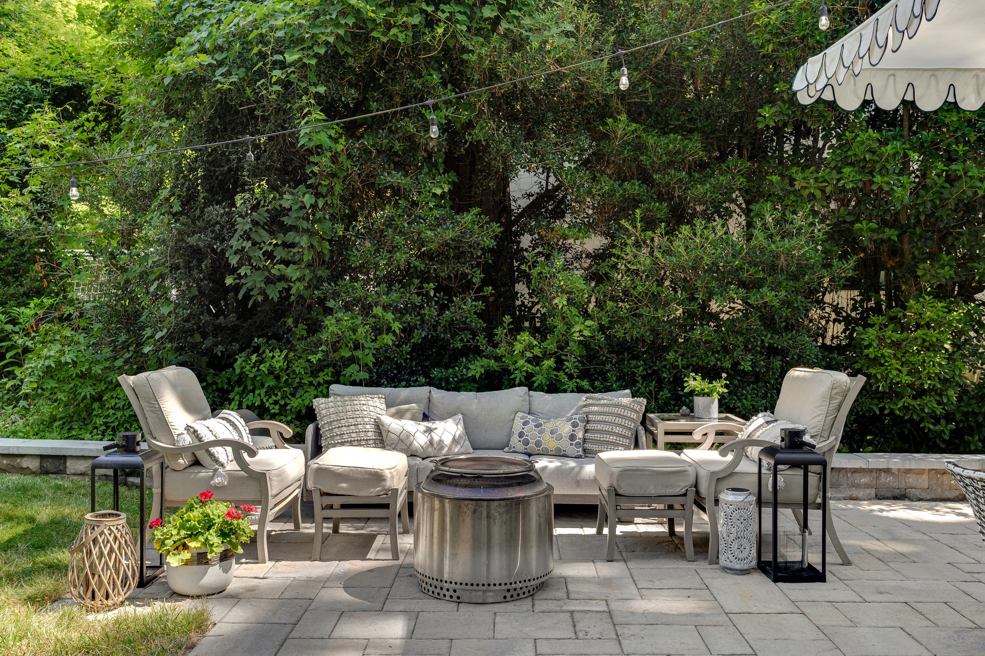 A cozy outdoor seating arrangement featuring cushioned chairs, a fire pit, and lush greenery in the background, perfect for relaxing and social gatherings amidst a serene natural setting.