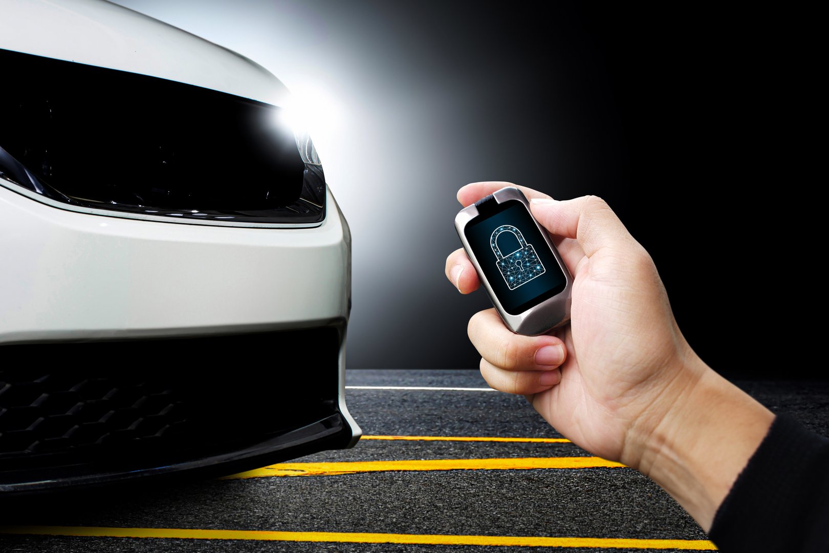 Driver hand holds keyless remote with key locked icon on display with white modern car parked on the road in the background , Technology concept for preventing car theft