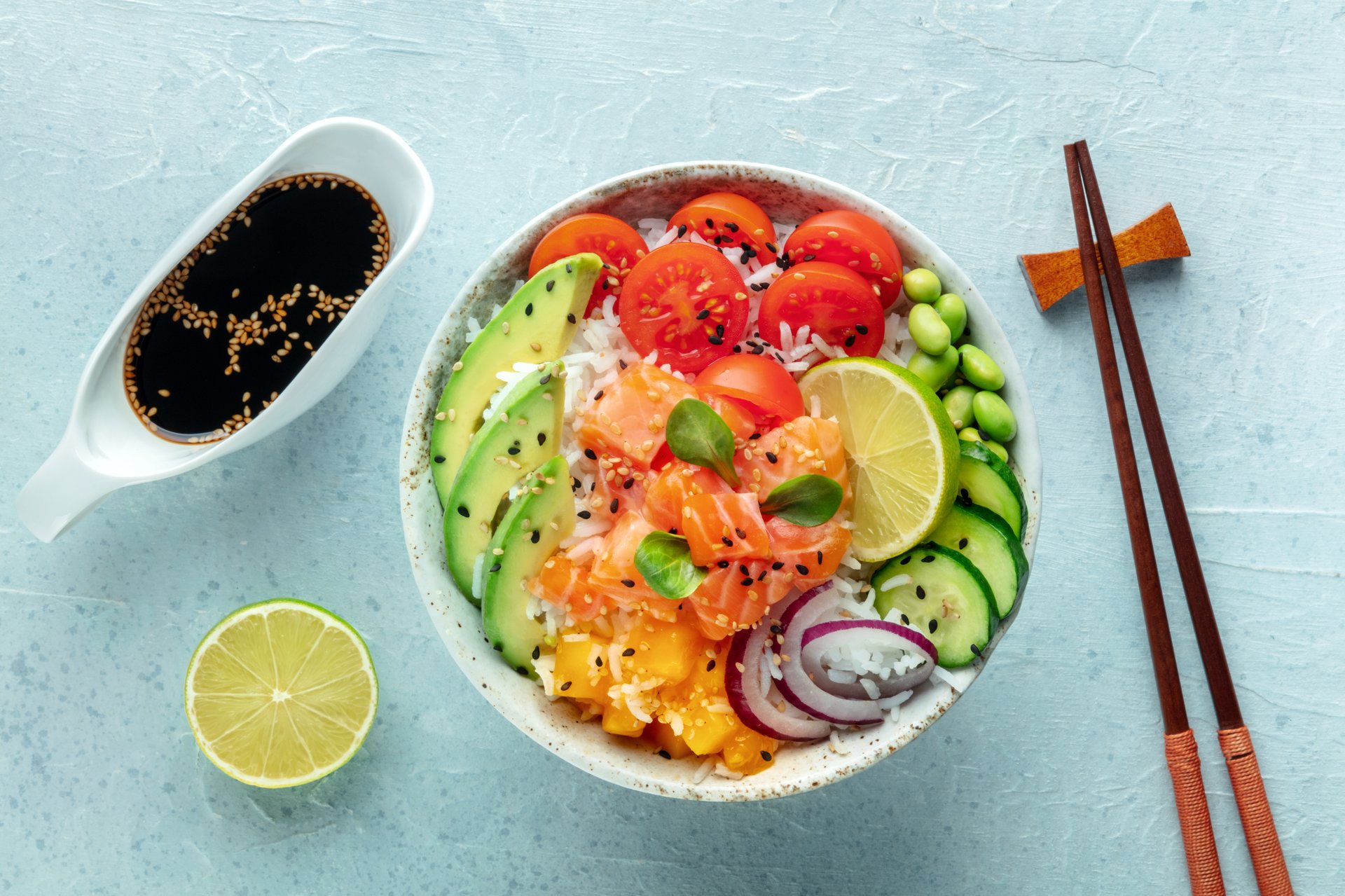 Poke bowl with salmon. Hawaiian salad with rice, fish, tomato, and avocado. Healthy diet. Overhead flat lay shot with chopsticks and soy sauce