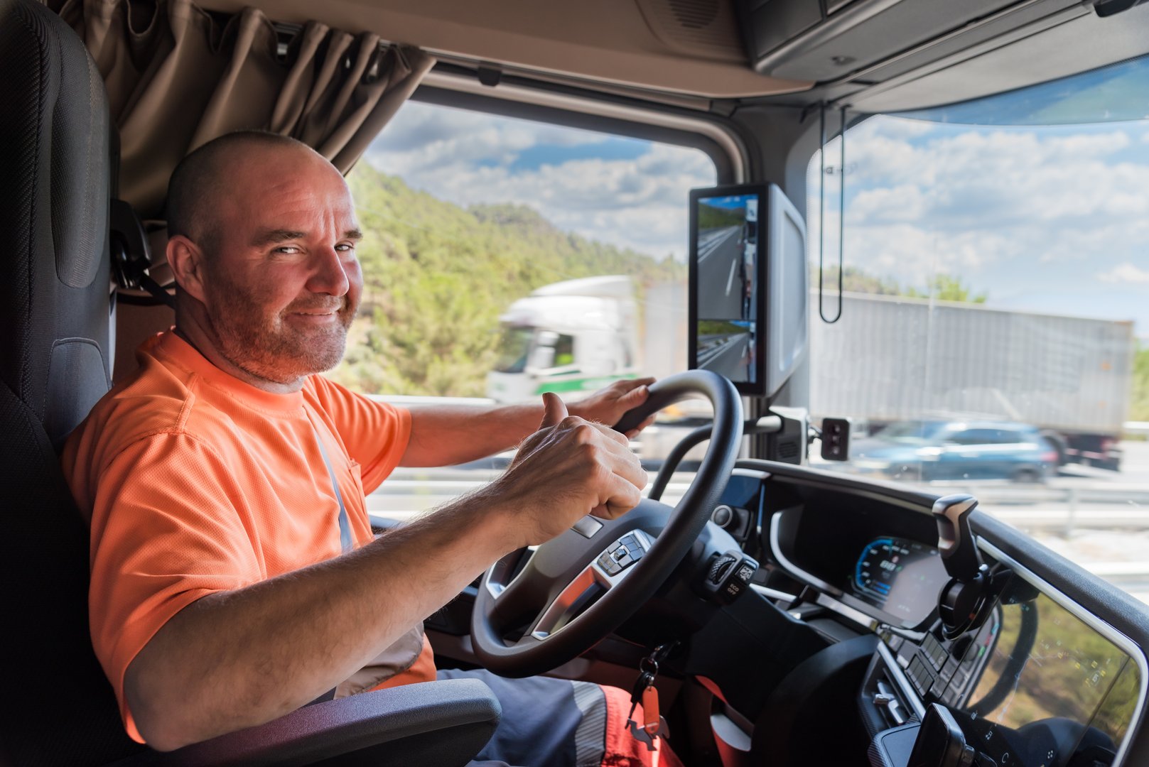 Truck driver driving on the highway with a happy expression and thumb up as an OK sign.