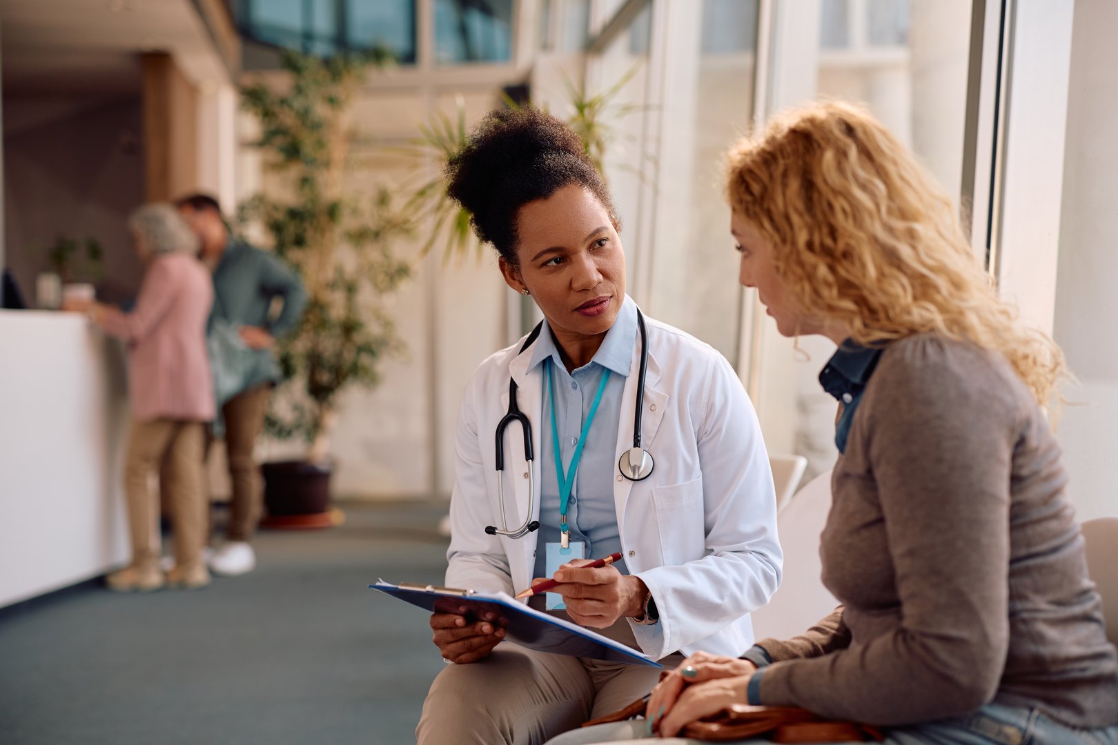 African American doctor and her female patient analyzing test results after medical examination at polyclinic.