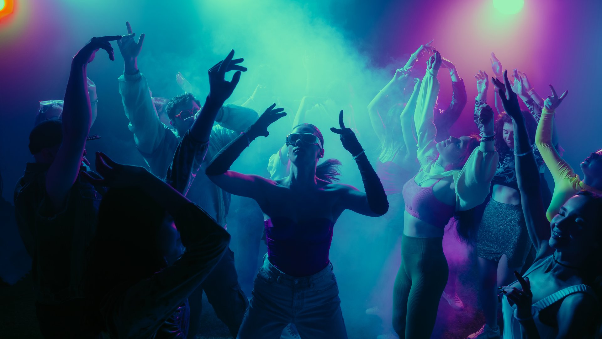 A vibrant party scene with diverse people dancing under colorful lights. Concept of nightlife party, youth, summer, festivity, celebration