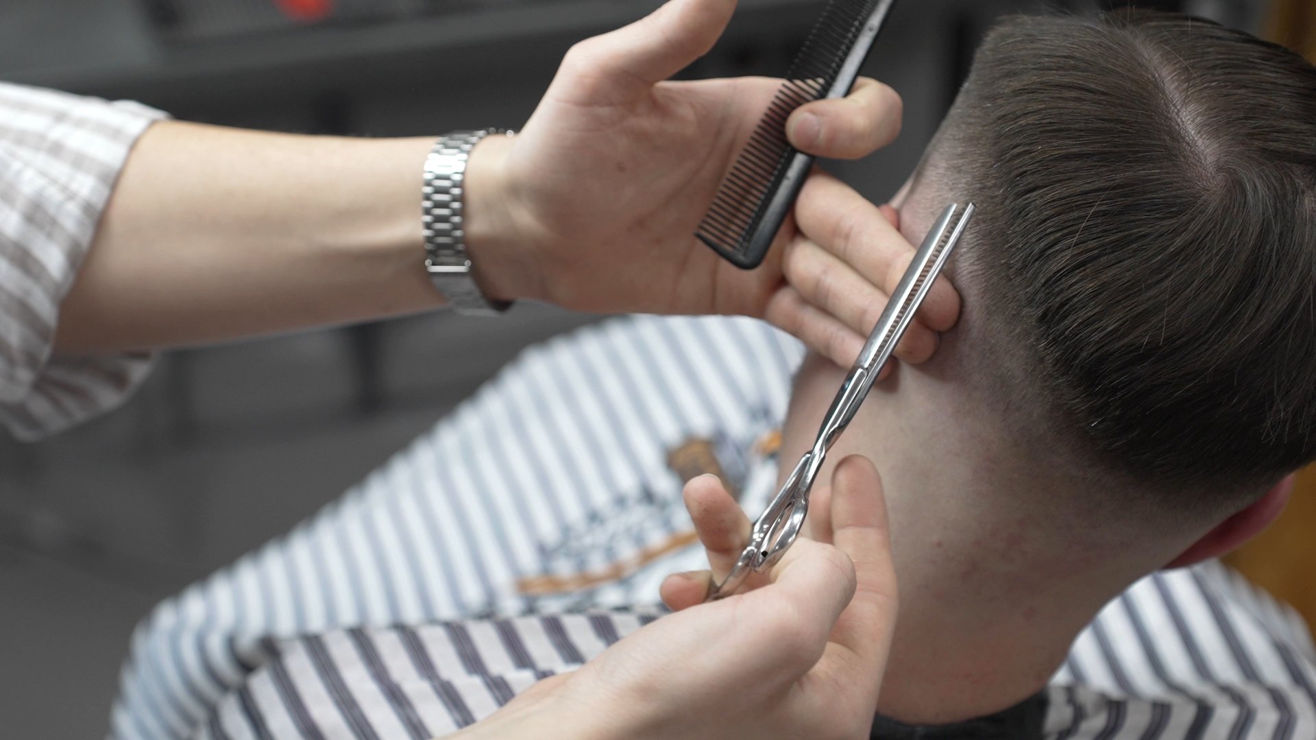 Professional barber trimming client's hair, crafting precise fade with scissors and comb in sleek contemporary barbershop setting, delivering expert grooming