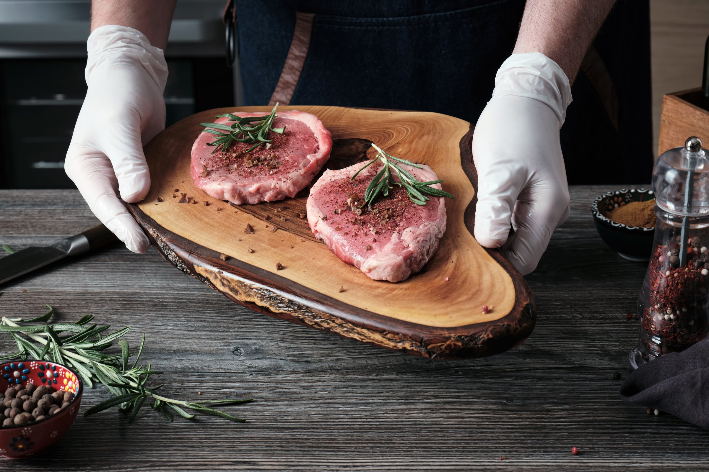 A man holds a wooden cutting board with raw marbled beef steaks prepared for cooking. Cooking at home.