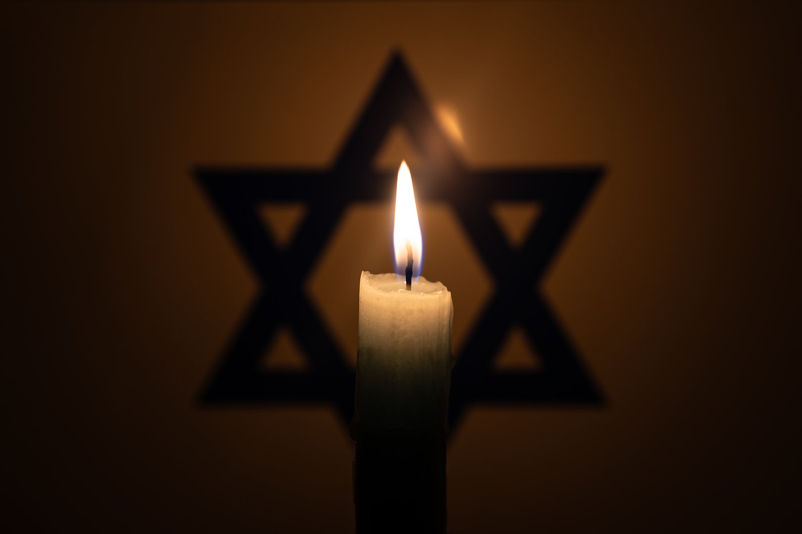 Burning candle on Israel flag background. International Holocaust Remembrance Day, January 27. war in Middle East