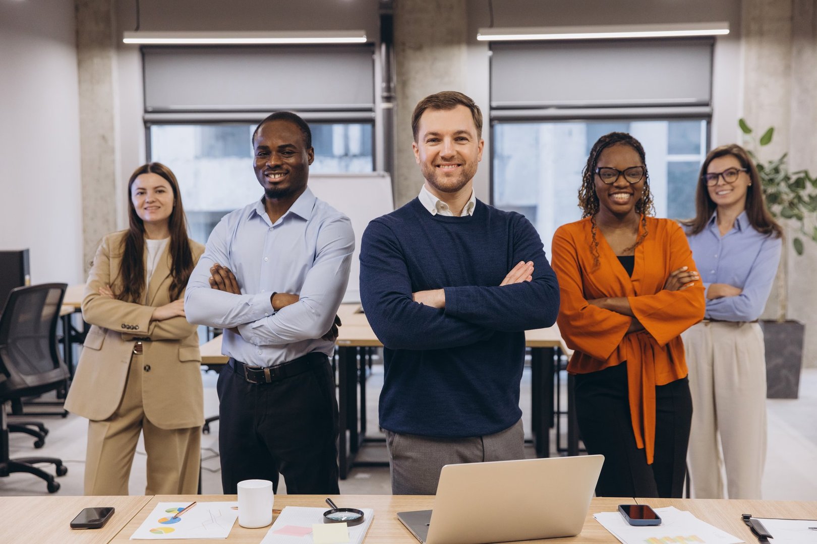 Diverse colleagues standing with arms crossed, showcasing teamwork and professionalism in a contemporary workspace