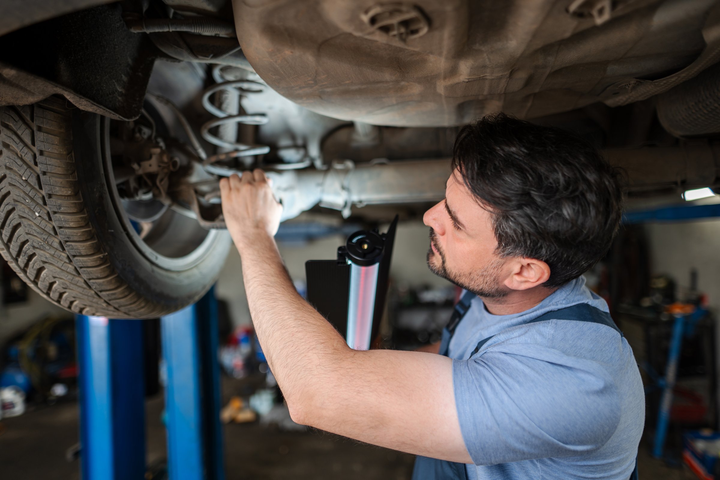Mecánico trabajando debajo de un автомóvilelevado