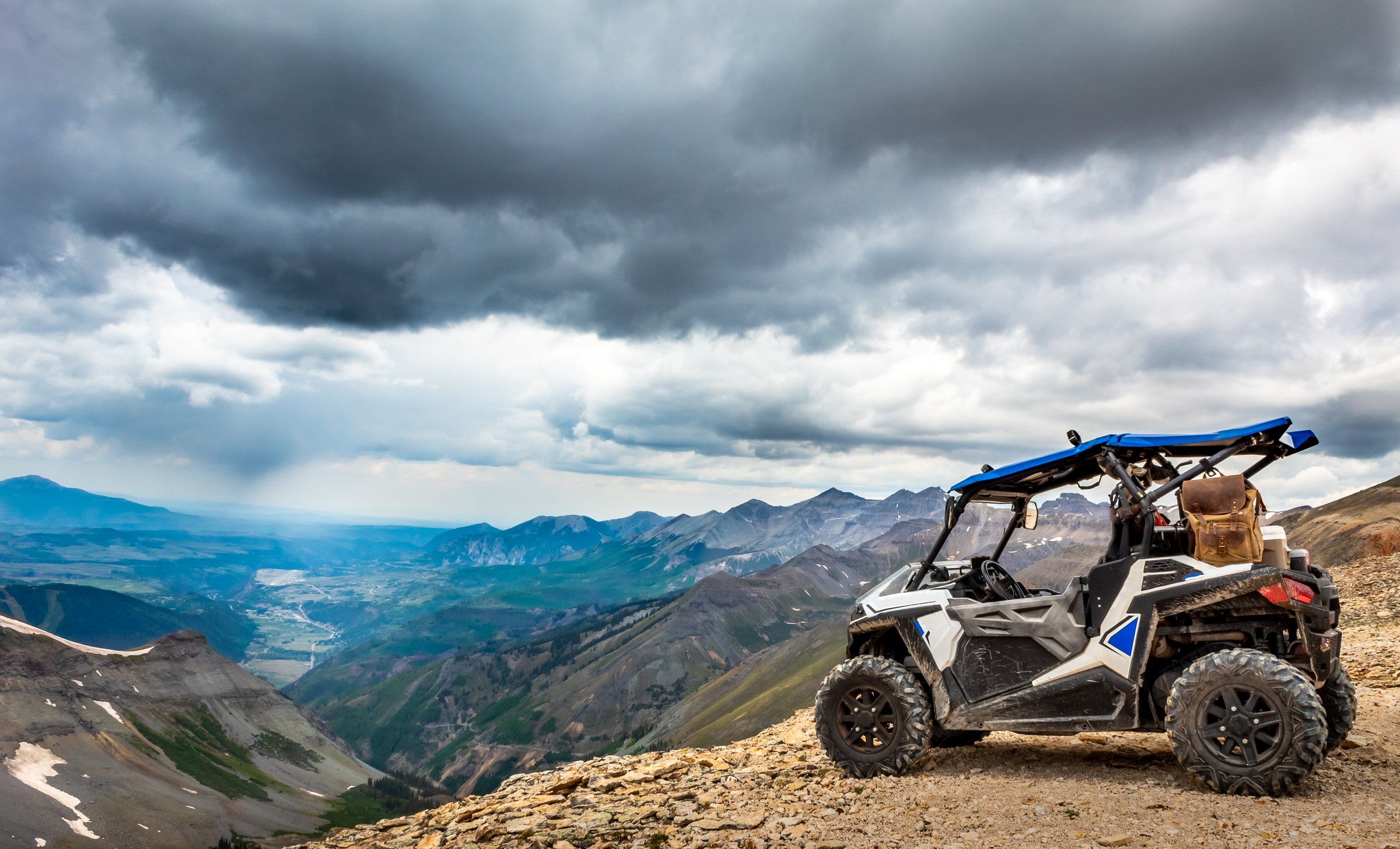 Side by side UTV ATV RZR with Mountain range in the background at the summit of Imogene pass near Silverton Telluride and Ouray Colorado in the San Juan Mountains, Rocky Mountains Colorado. Telluride, Colorado in the distance.