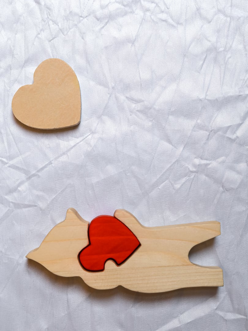 Wooden puzzle with a red heart and a separate wooden heart on a textured background.Concept of Valentine's Day greeting, symbolic love message, personalized romantic gift, handcrafted decor for celebrations and special occasions.