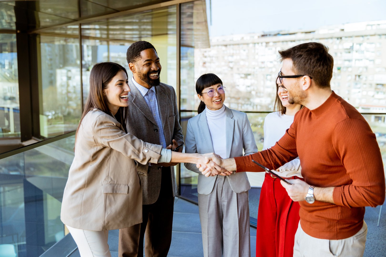 A lively gathering of professionals in a bright office as they shake hands, share smiles, and discuss innovative strategies, fostering collaboration and connection among team members.