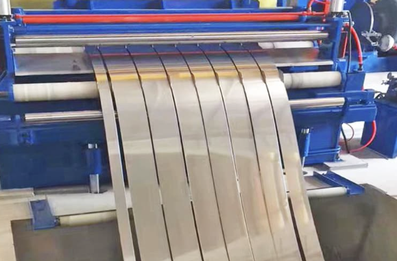 Metal slitting machine cutting sheets into thin strips in a factory setting.