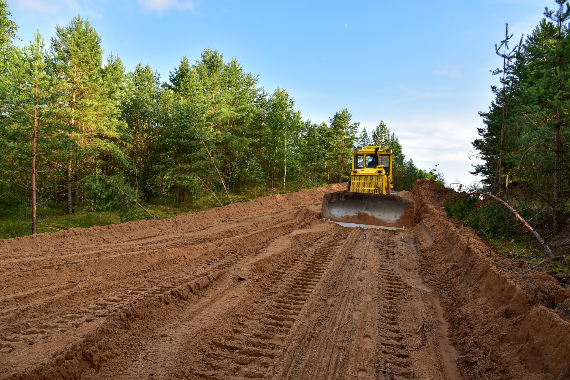 Dozer during clearing forest for construction new road . Yellow Bulldozer at forestry work Earth-moving equipment at road work, land clearing, grading, pool excavation, utility trenching