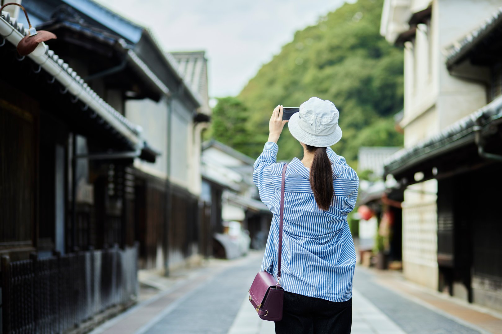 A traveling Japanese woman taking photos with her smartphone at a tourist spot
