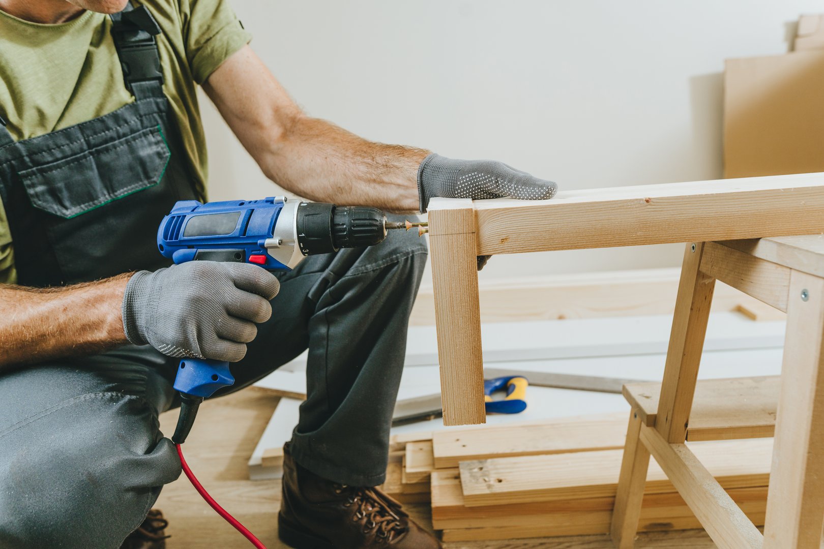 Close up of carpenter drilling a board with a screwdriver. Professional woodworker using tools for work in his workshop. Small business concept.