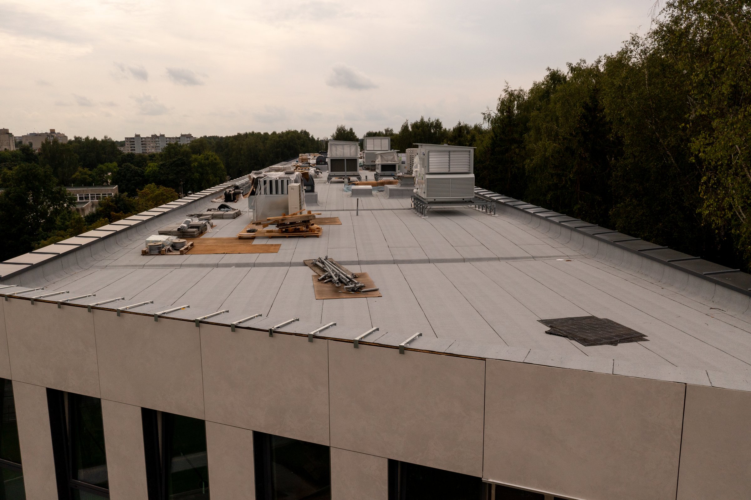 Drone photography of new building rooftop being built with construction equipment during summer cloudy day