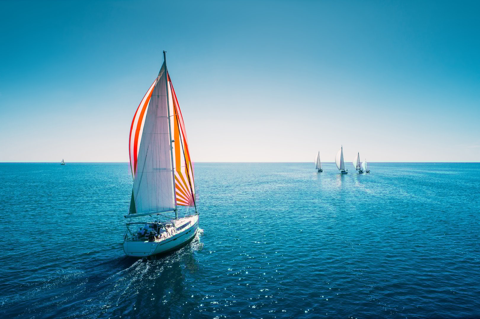 Regatta sailing ship yachts with white sails at opened sea. Aerial view of sailboat in windy condition.