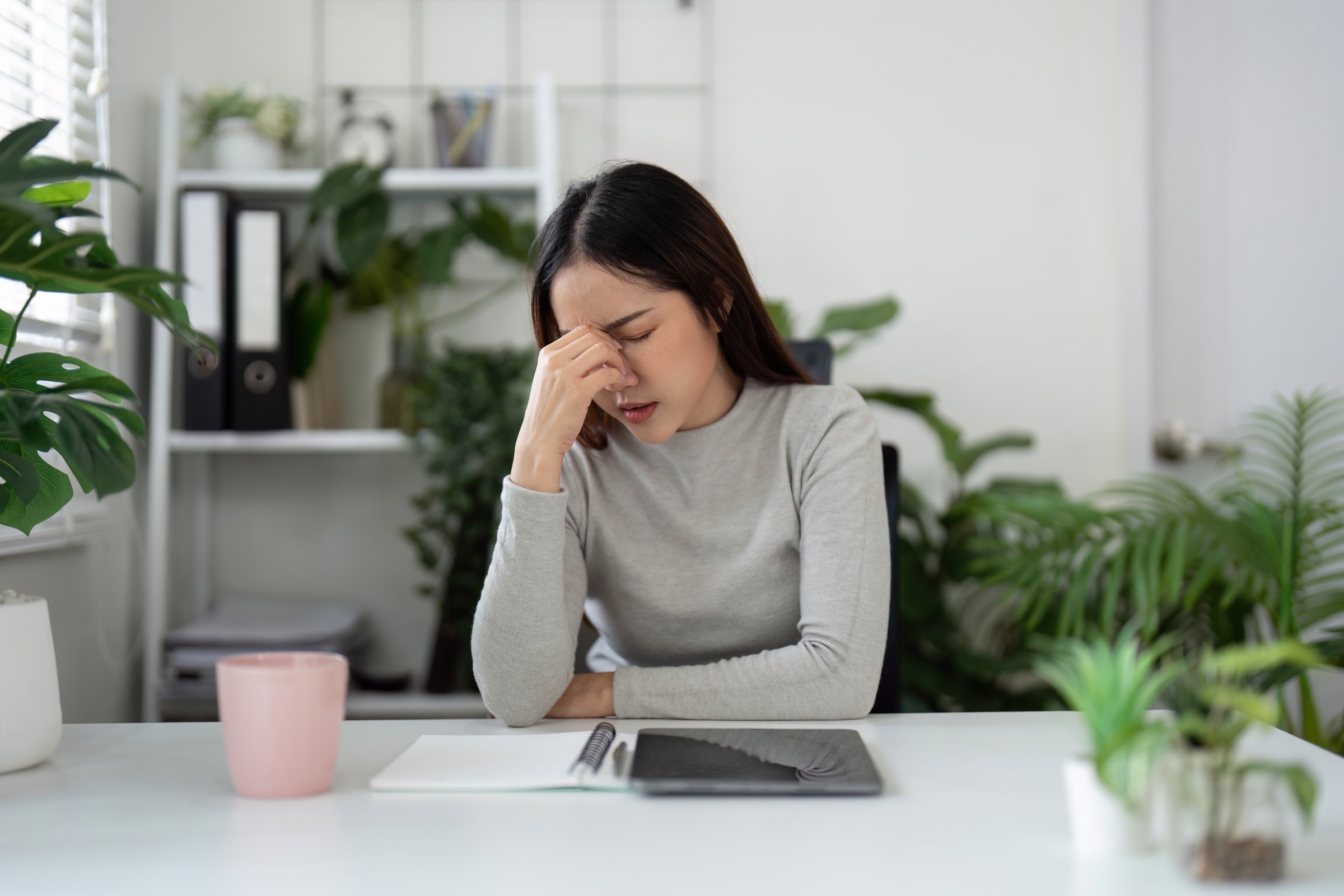 A woman at her desk looks stressed, emphasizing the importance of mental health and well-being in the workplace.