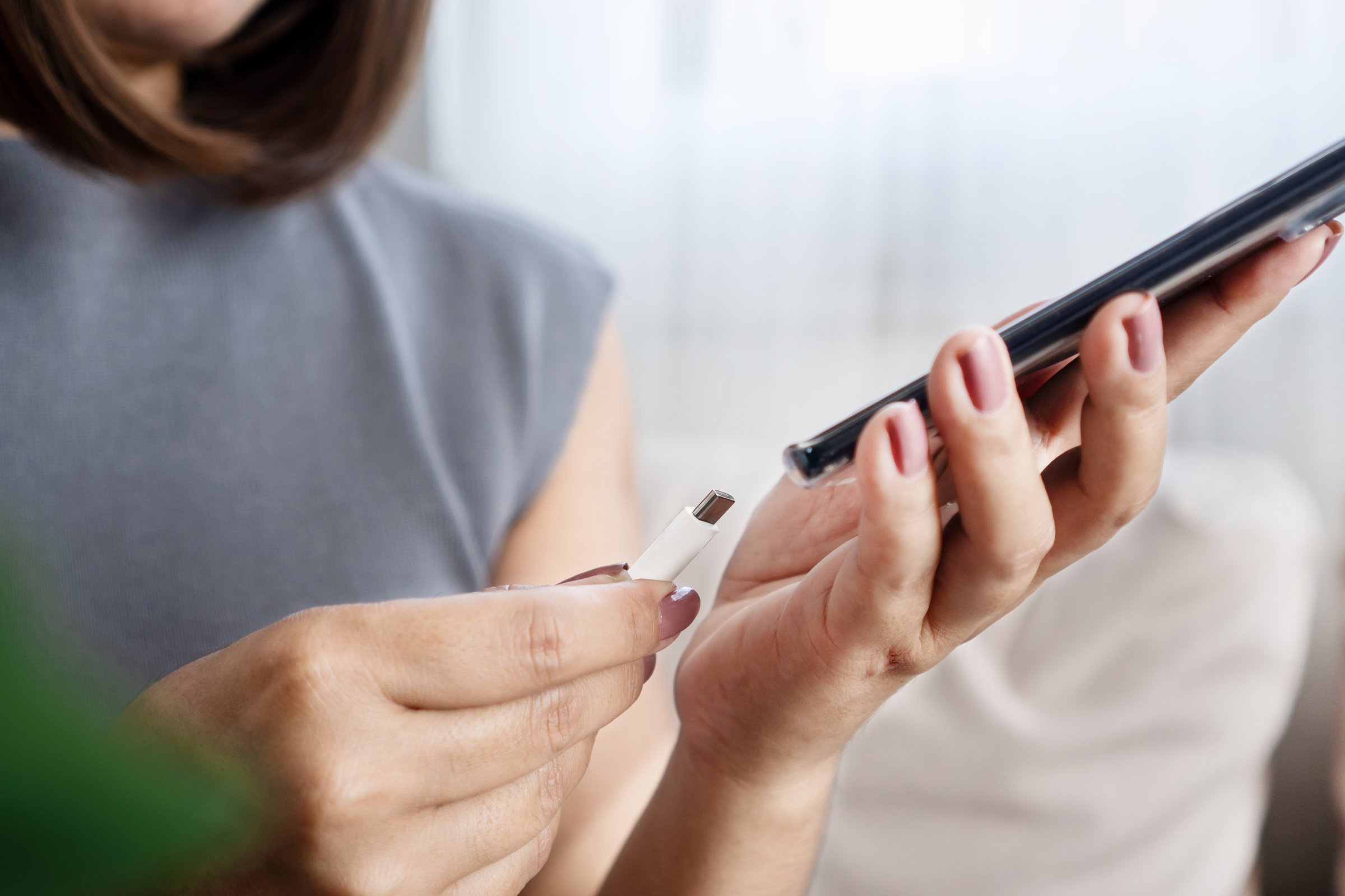 close-up of a woman's hand charging a low battery mobile phone at home