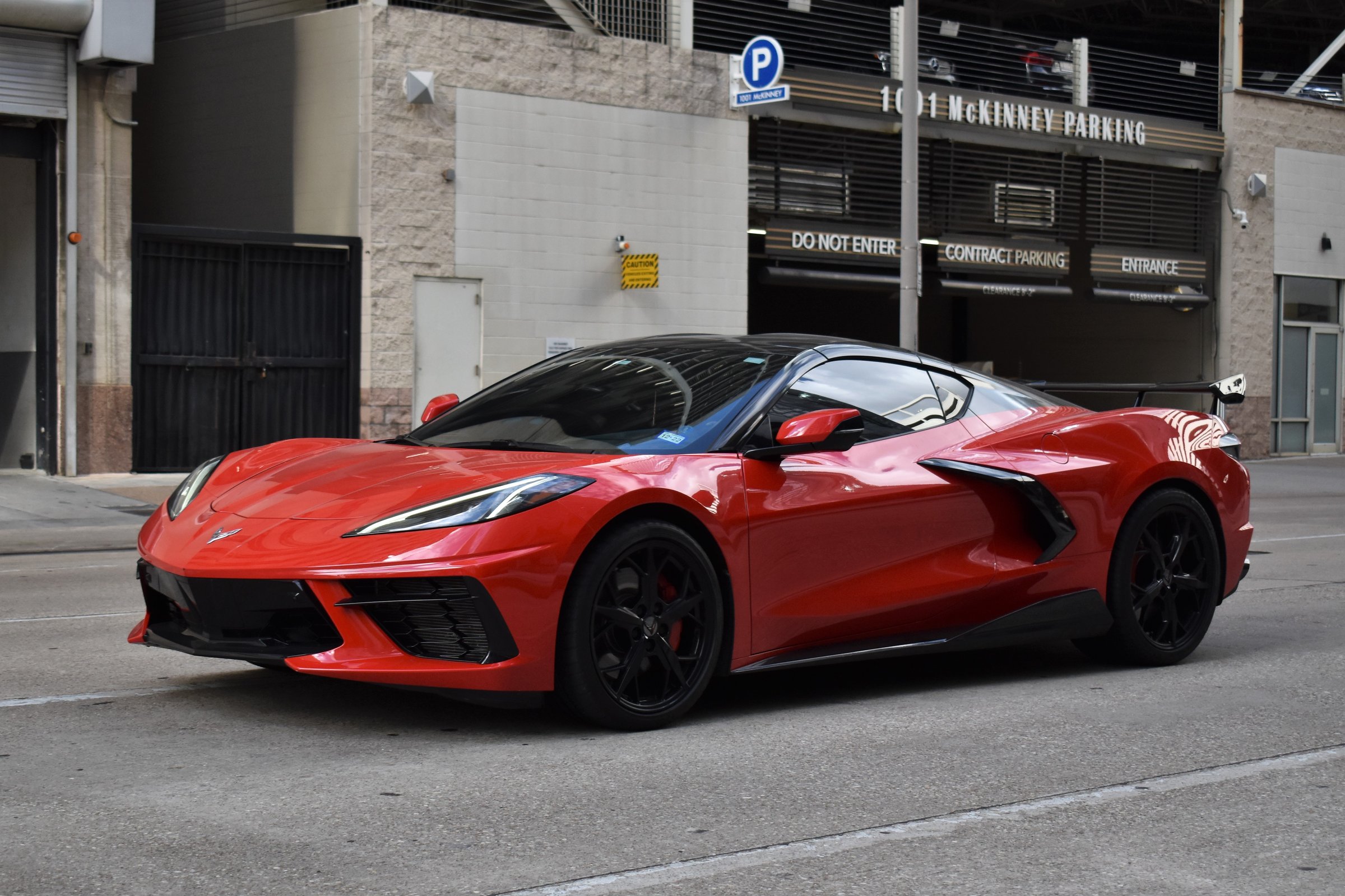 Houston, TX USA 10-4-2024 - A portrait of a red and black Chevy Corvette C8 3LT sports car traveling near the McKenney Parking Garage in the downtown financial district of Houston.