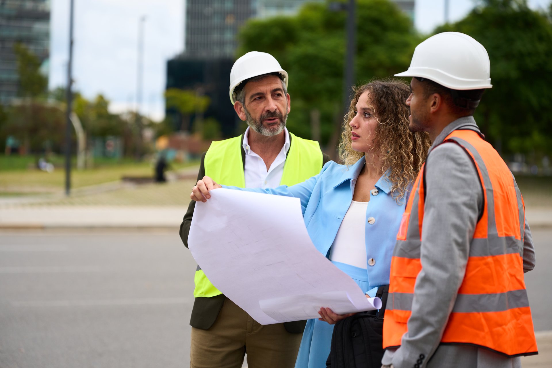 Diverse construction team collaborating on site, reviewing building plans and discussing urban development project