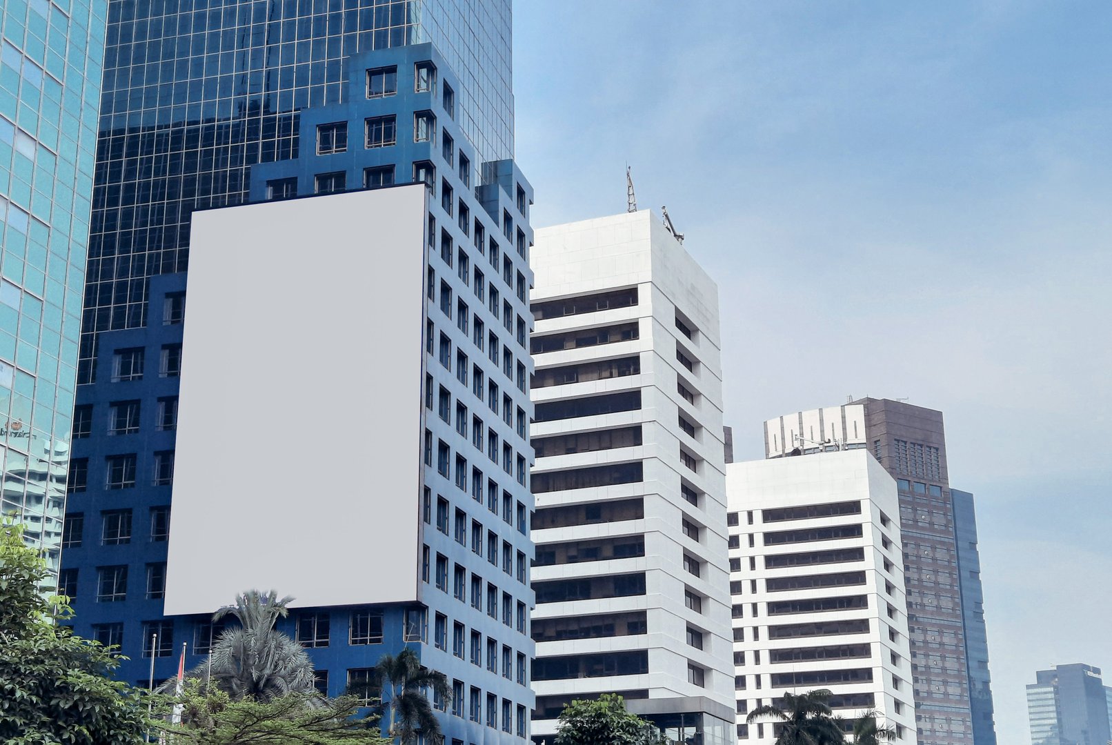 Large blank advertising billboard on modern building against clear blue sky. Ads mockup.