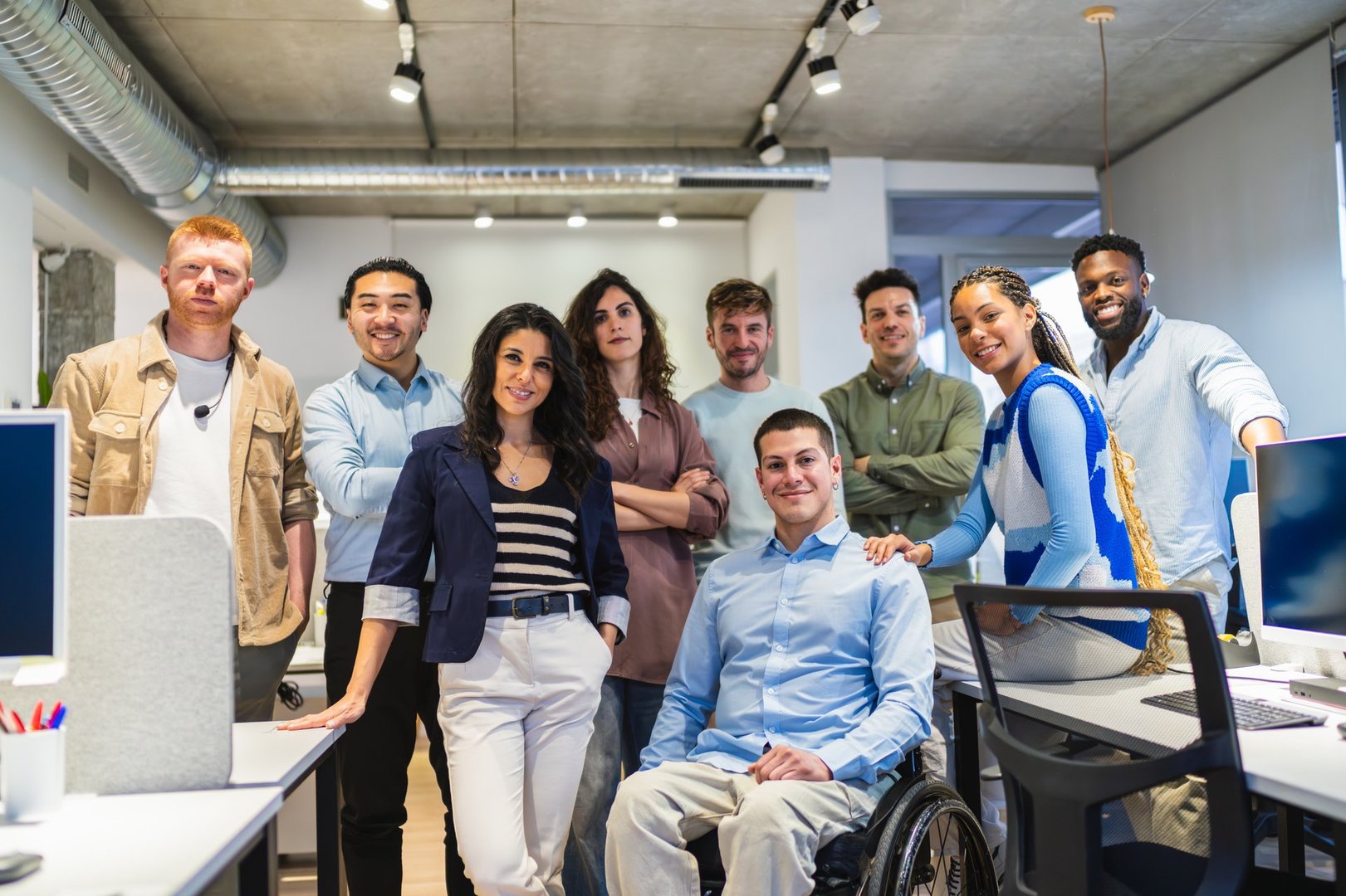 Diverse group of professionals smiling at the camera in a bright office environment, showcasing teamwork and inclusion
