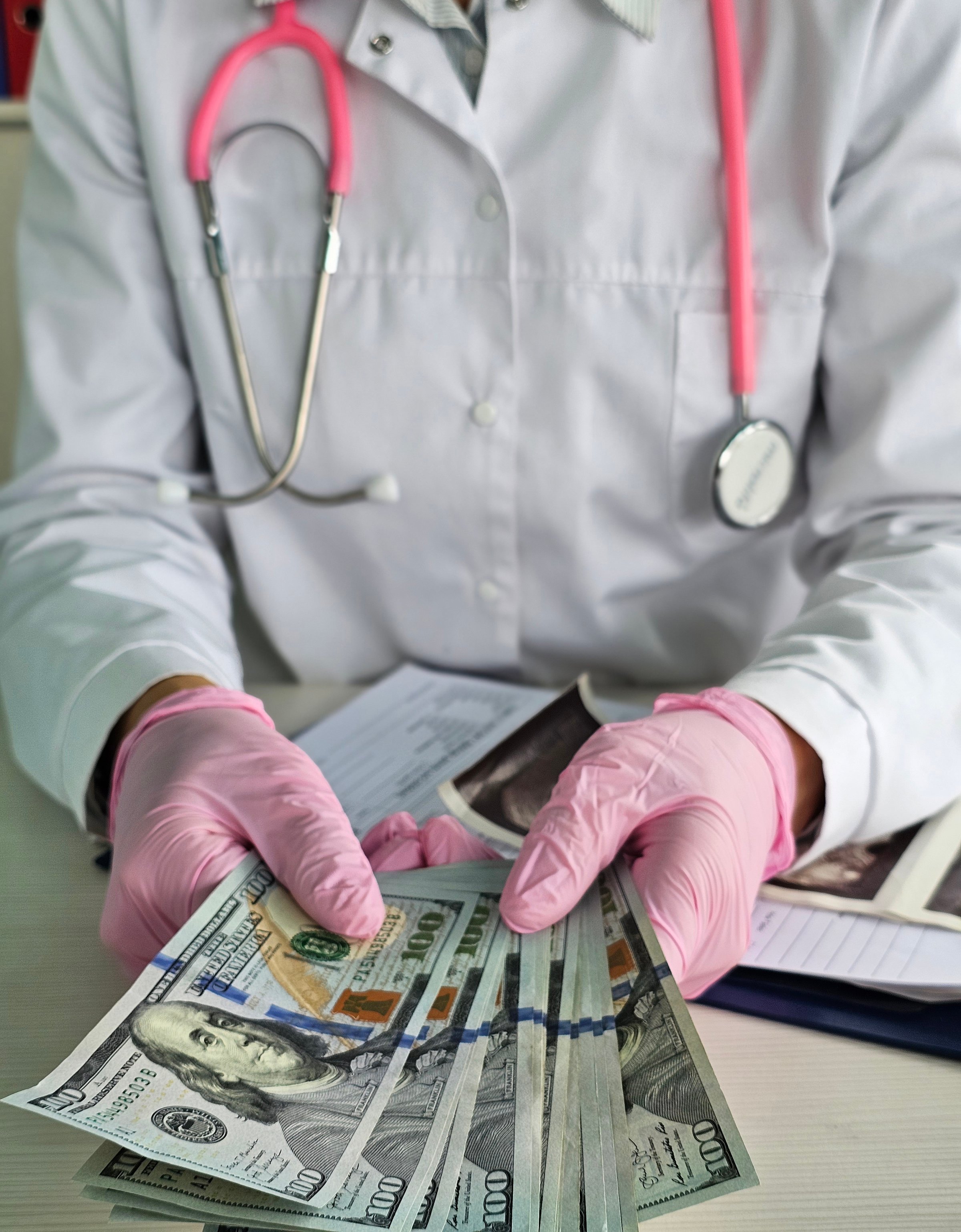 Doctor in white coat holding cash with gloved hands in a healthcare setting