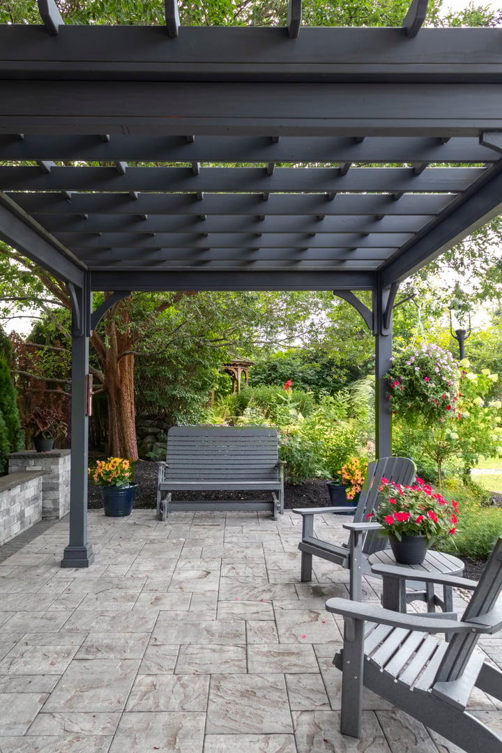 Wooden gray pergola on pavers with stone fireplace and waterfall urns landscape design idea for backyard sanctuary