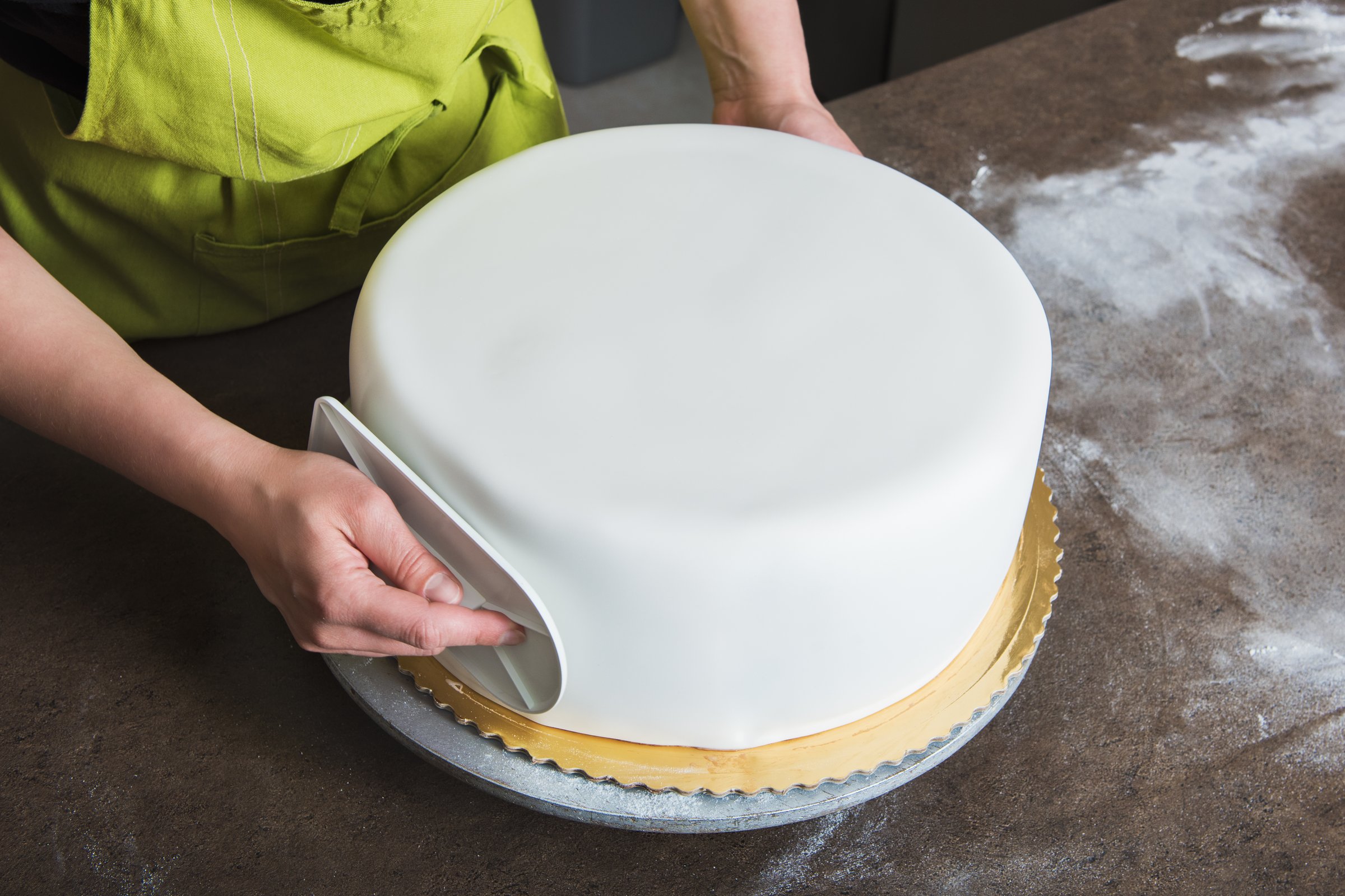 Pastelera profesional trabajando con fondant blanco en un pastel de boda