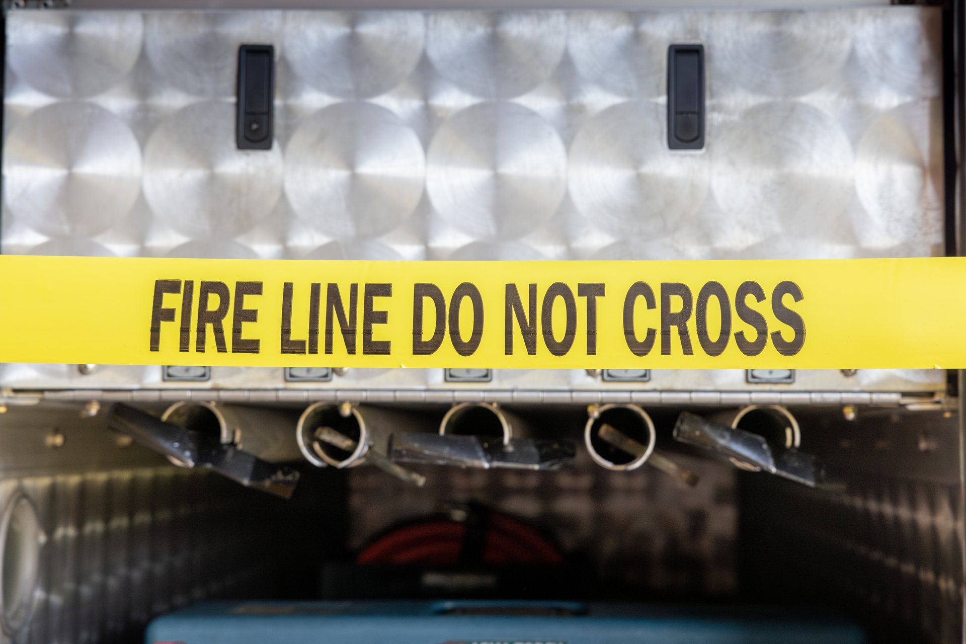 Warning tape extended in front of an open hatch on a fire truck