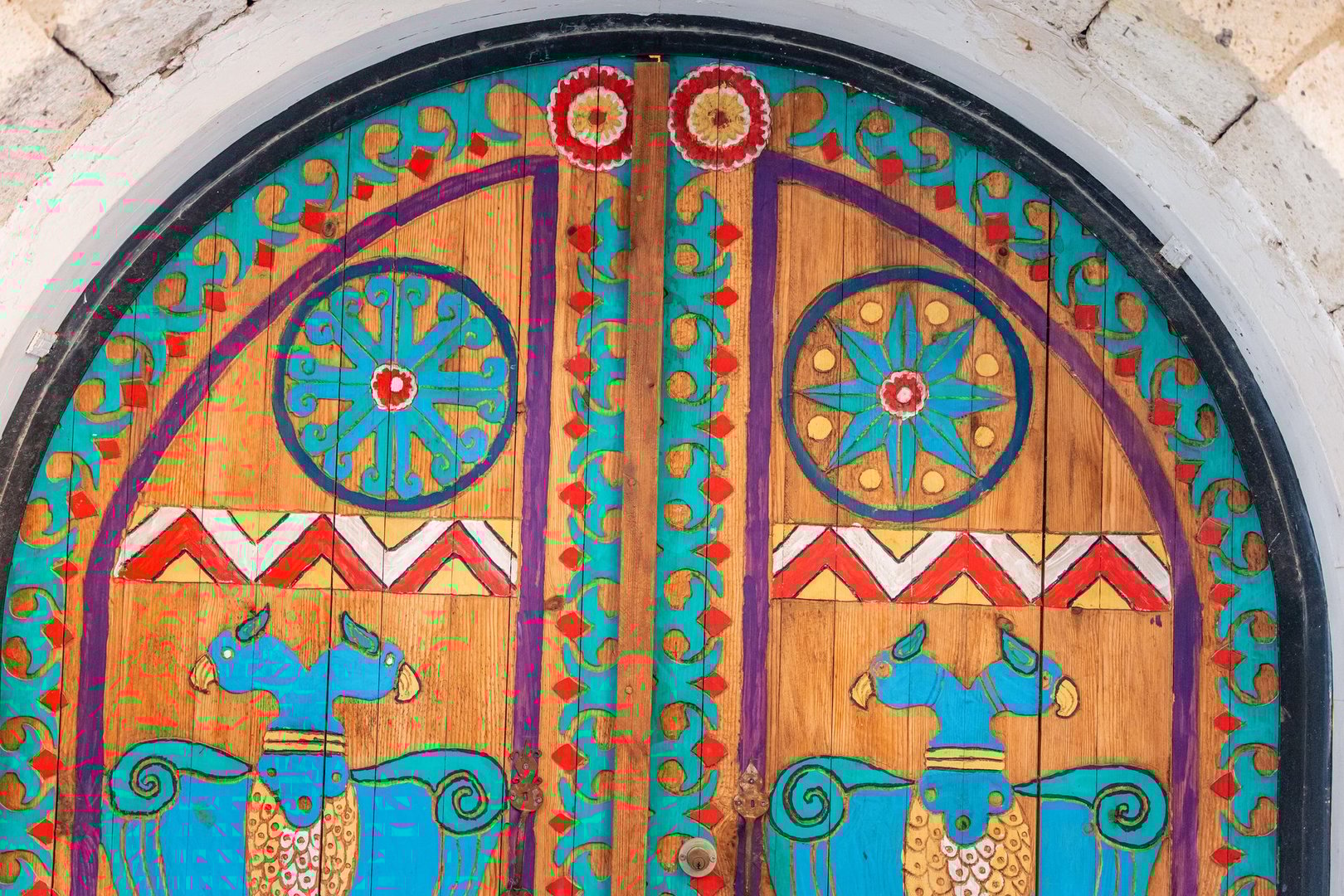 29 April 2025, Alacati, Turkiye: Traditional wooden door decorated with colorful patterns including two mythical birds, and floral motifs