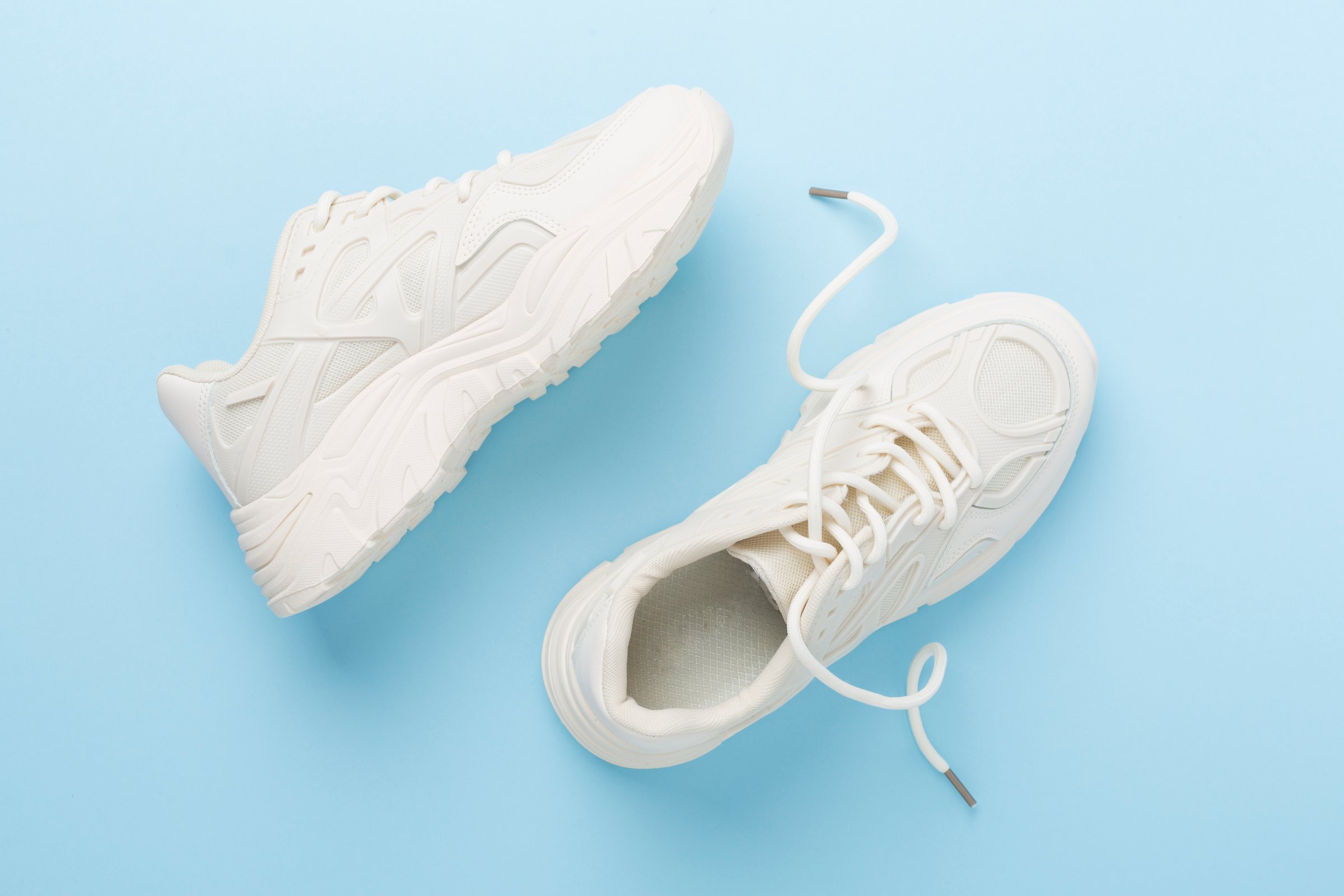 White woman trendy sneakers on color background, top view