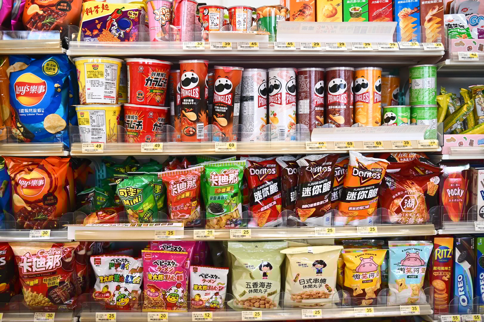 A vibrant display of chips, corn snacks, and instant noodle snacks fills the convenience store shelves, showcasing a variety of flavors and textures.