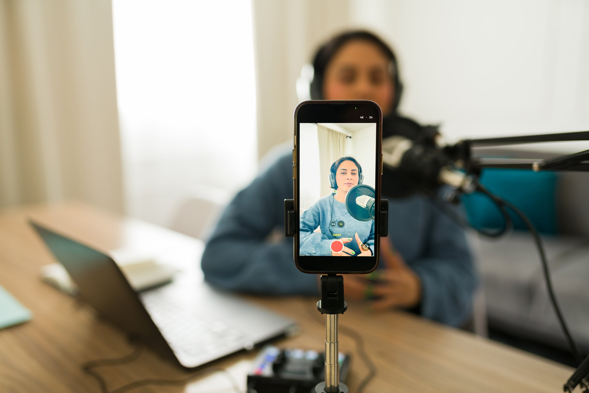 Young woman recording audio and streaming video with smartphone for her podcast or online radio show