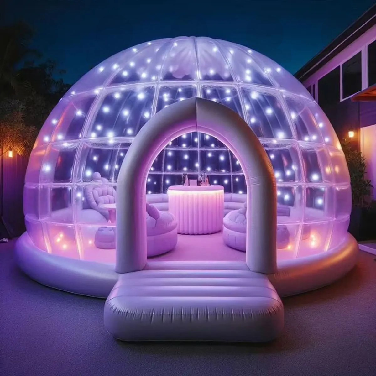 Inflatable clear dome tent lit with colorful LED lights, featuring cozy seating and a table inside, set outdoors at night.