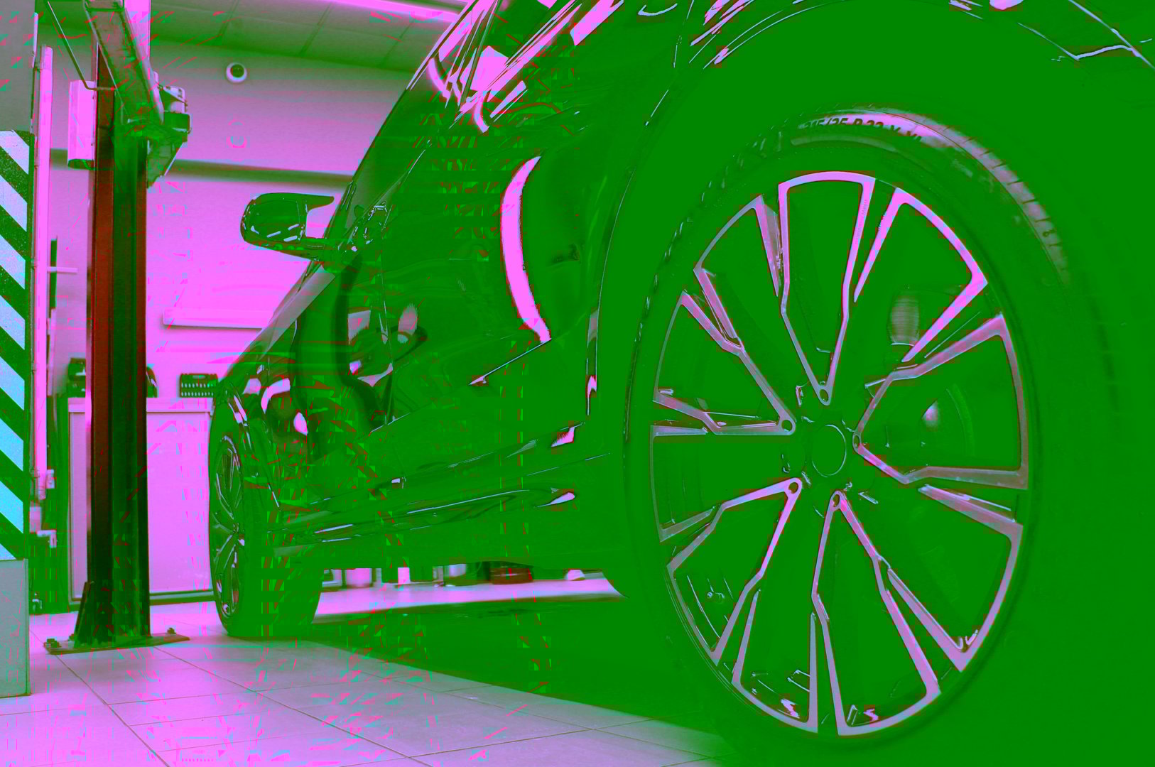 Black shiny SUV at a service station between lifts with shelves with tools rack in the background