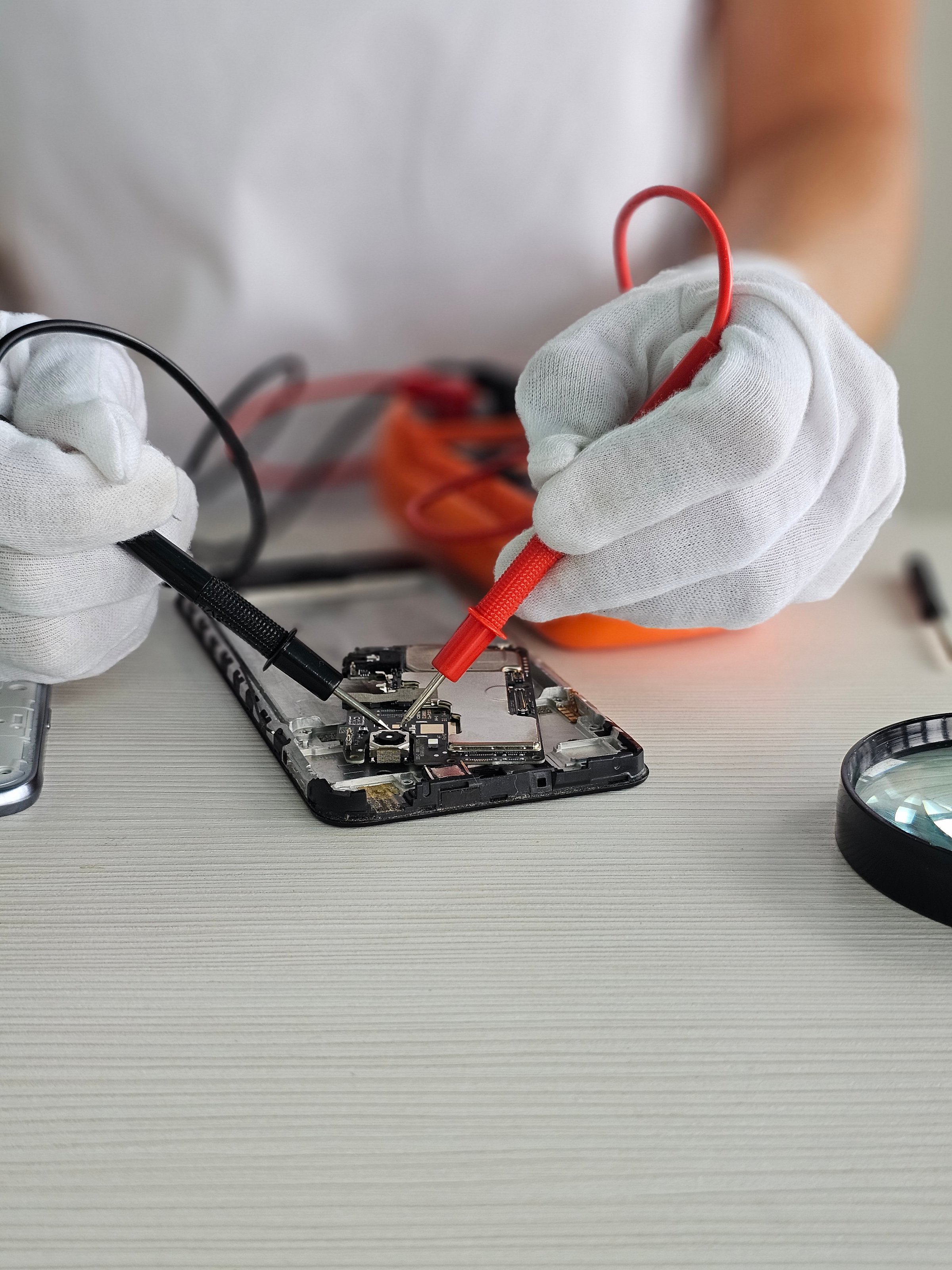 Repairing smartphone circuit with tools and testing equipment in a bright workspace during daytime