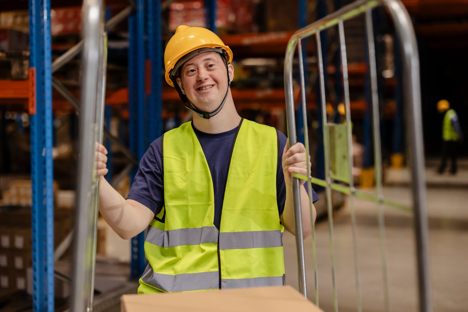 Smiling warehouse worker with Down syndrome in safety gear, highlighting workplace diversity and inclusion.