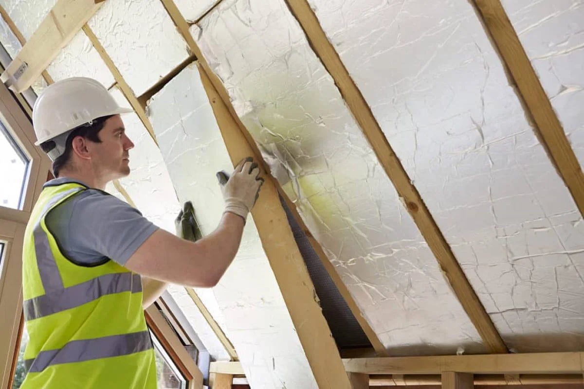 Construction worker installing PIR insulation boards on new build house