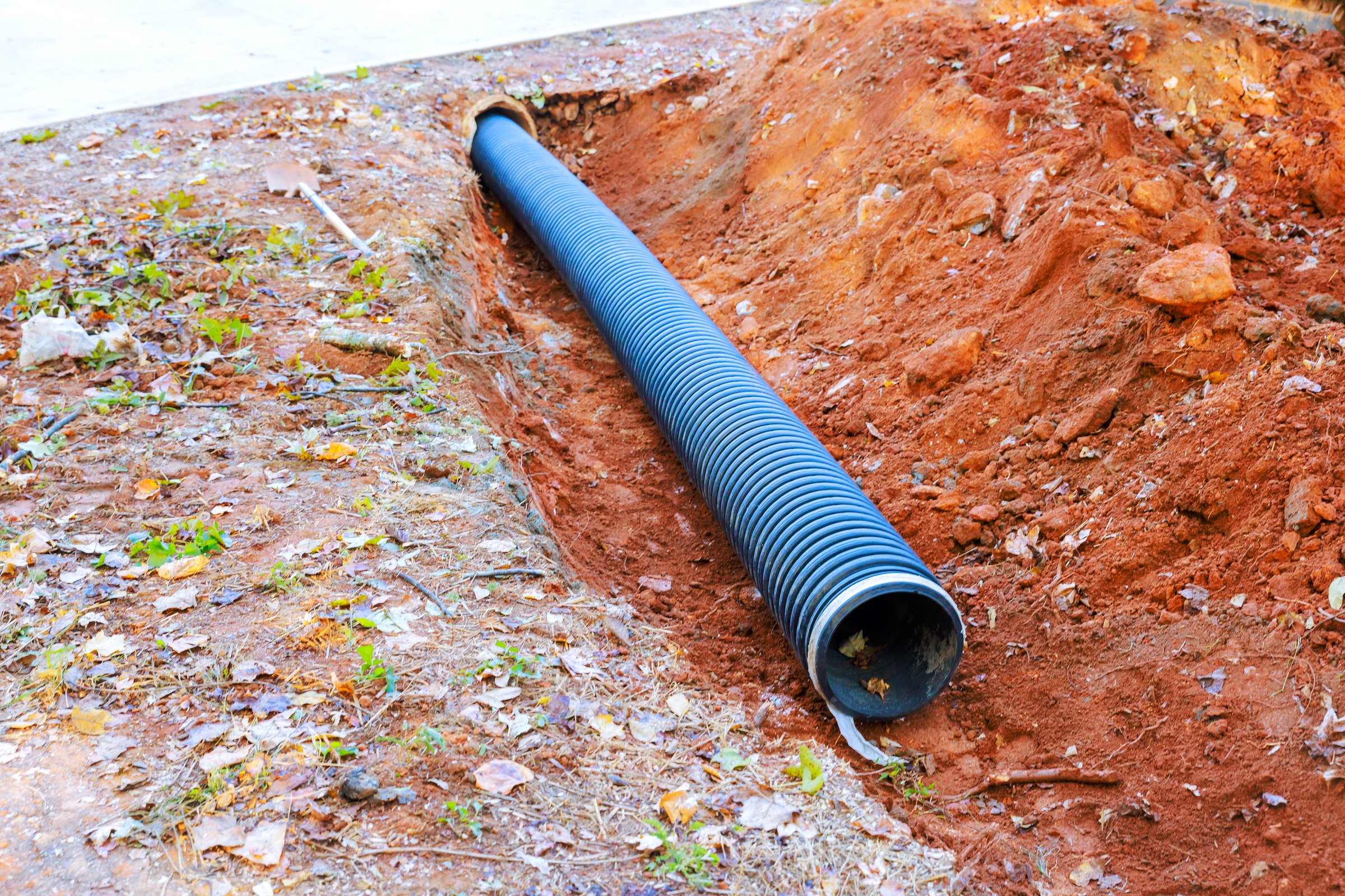 Excavation site with newly installed drainage pipe positioned in trench during construction work