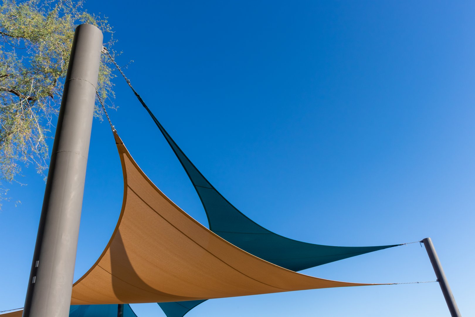Tan and blue canvas shade structures against a dark blue sky