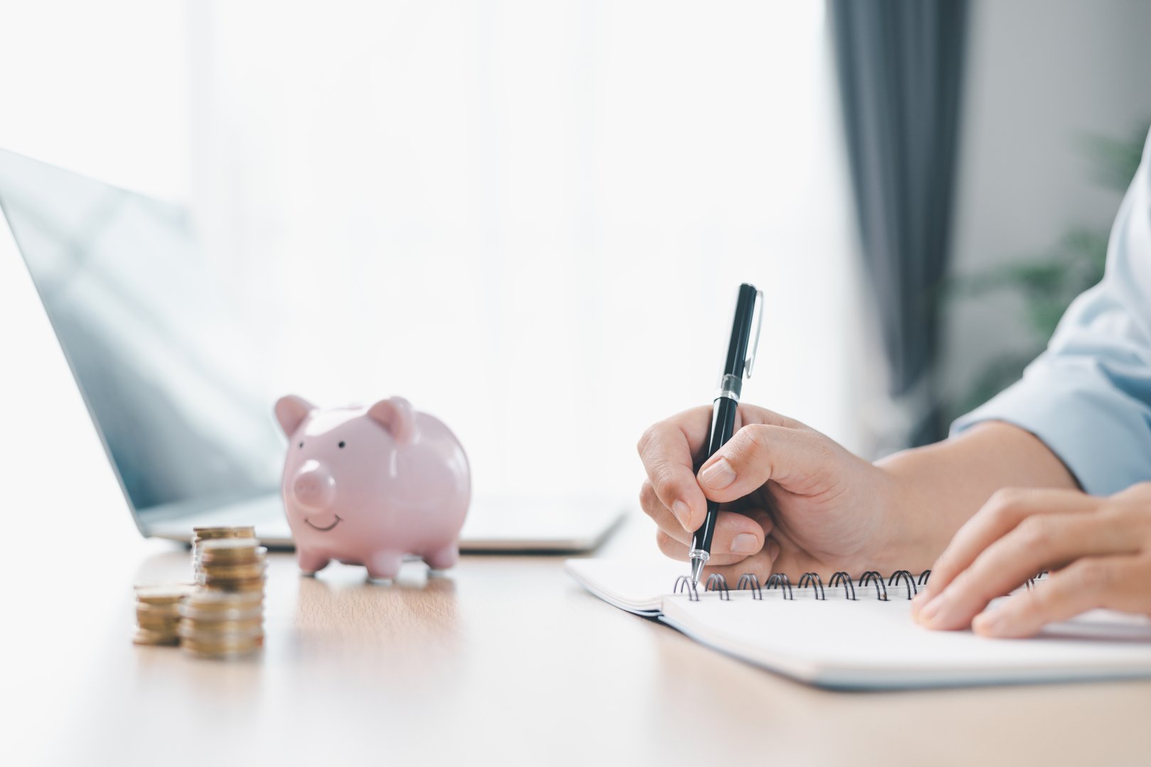 Concept of saving money and financial security. Pink piggy bank surrounded by coins on office desk with businesswoman in background, symbolizing investment, wealth growth and budget management.