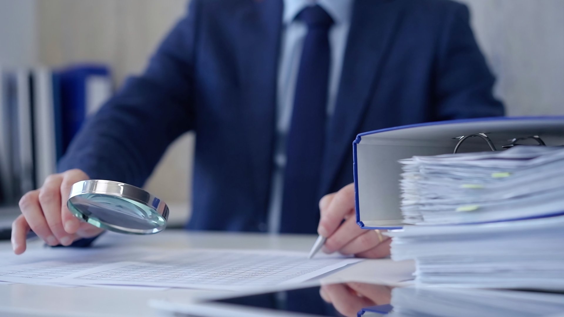 Businessman is carefully examining financial documents with a magnifying glass, highlighting the importance of thorough analysis in business. Audit and taxes.