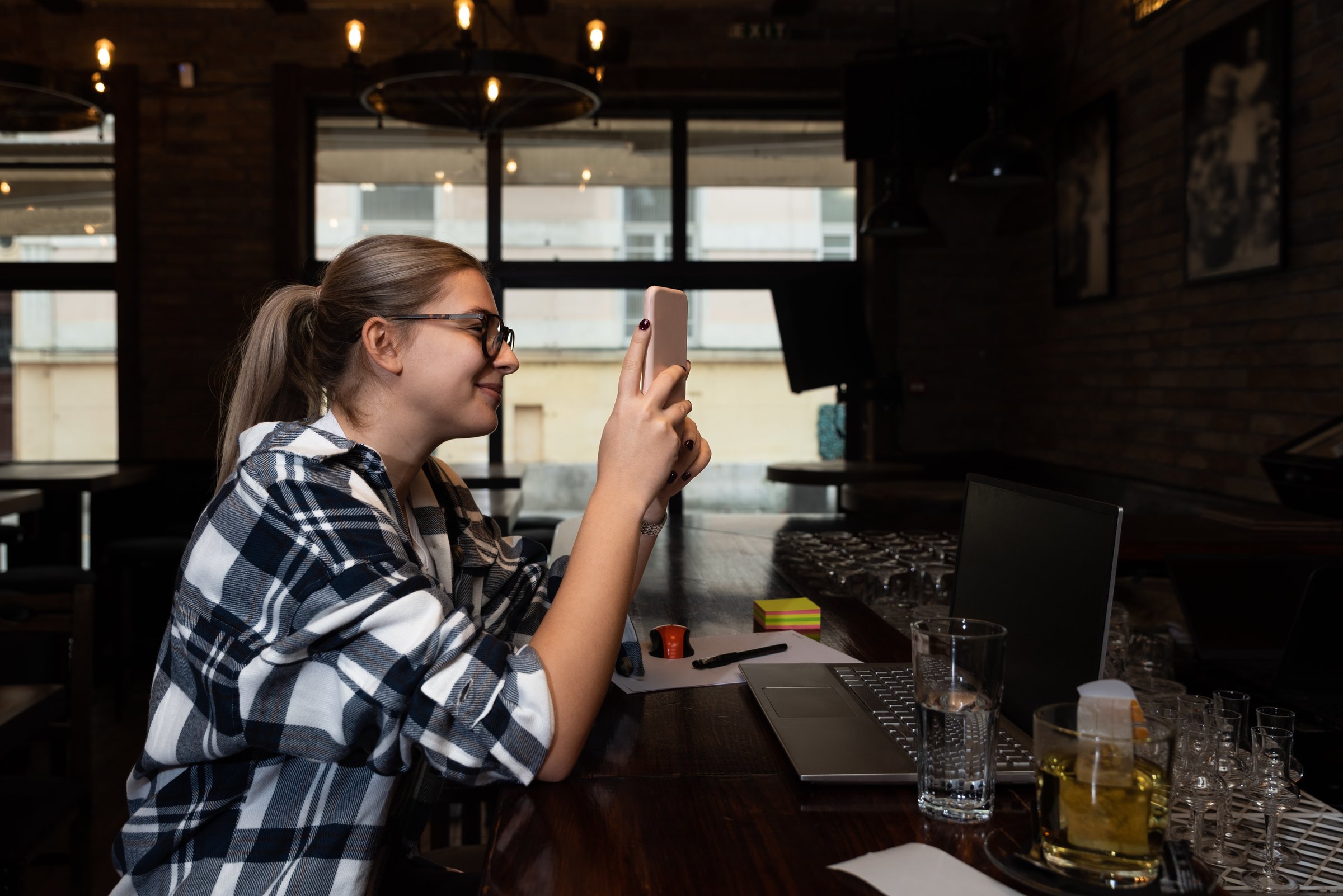 Young hipster freelancer business woman or college student sitting in cafeteria waiting for lunch. Expat businessperson on lunch break in restaurant waiting for table to sit and eat.