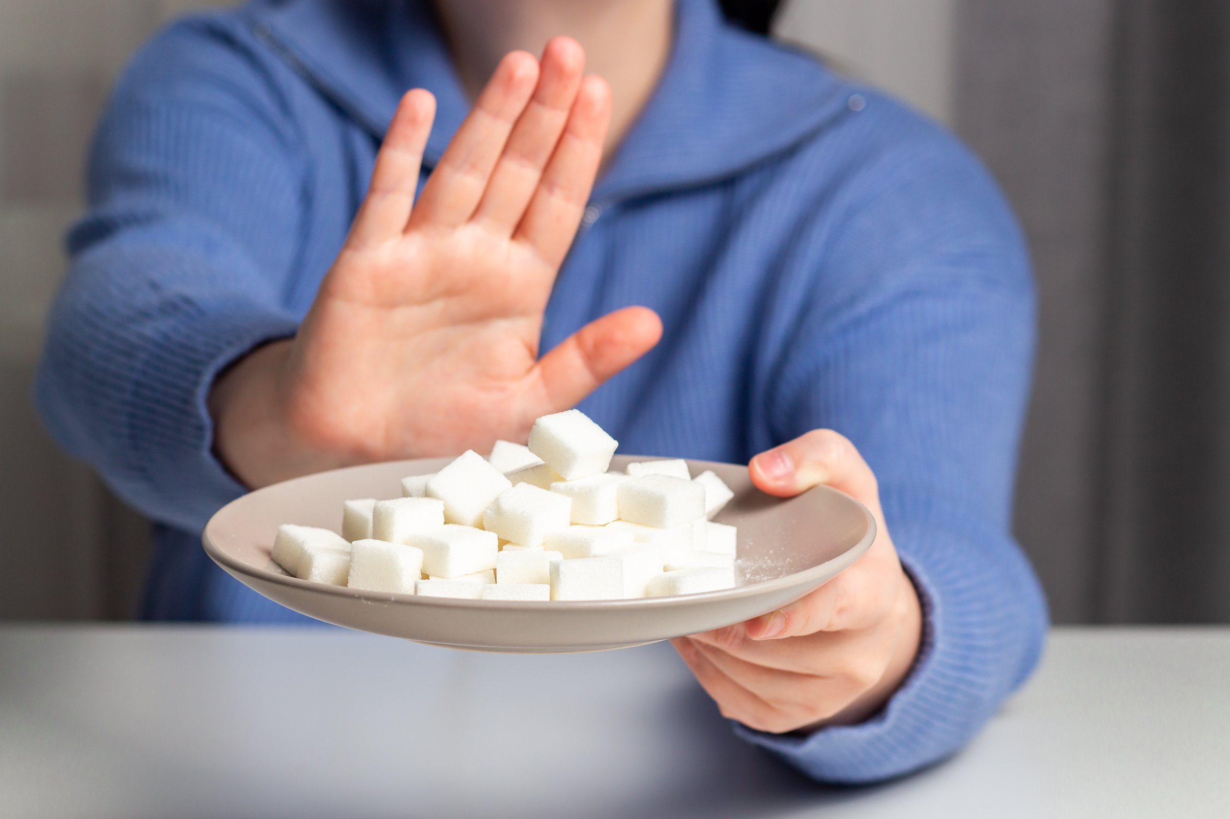 Woman on diet refuses to eat sugar. Hand sign rejecting sugar in food. Diabetes disease concept. 14 November.