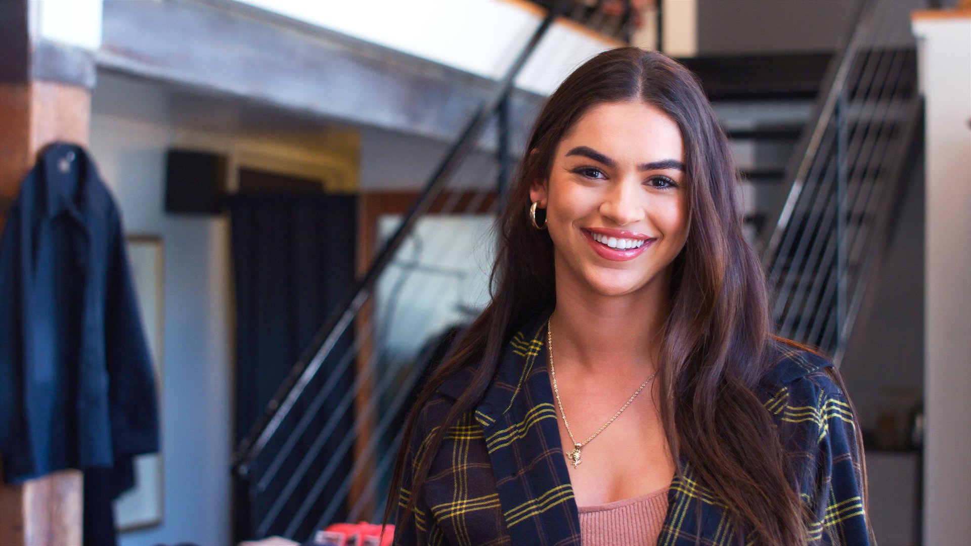 Portrait Of Smiling Female Owner Of Fashion Store Standing In Front Of Clothing Display